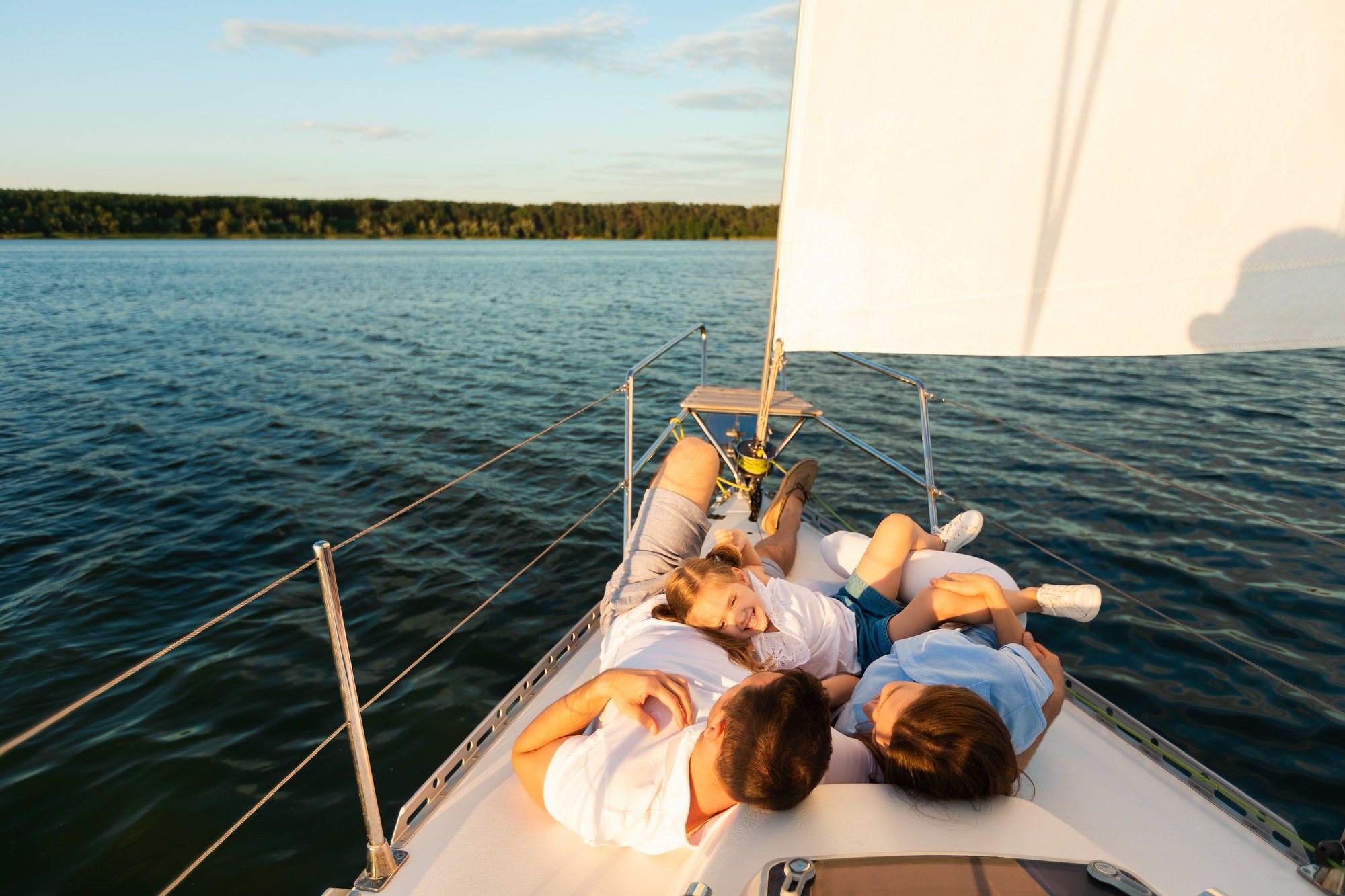 Family Lying On Yacht Deck Relaxing On Sailboat Ride